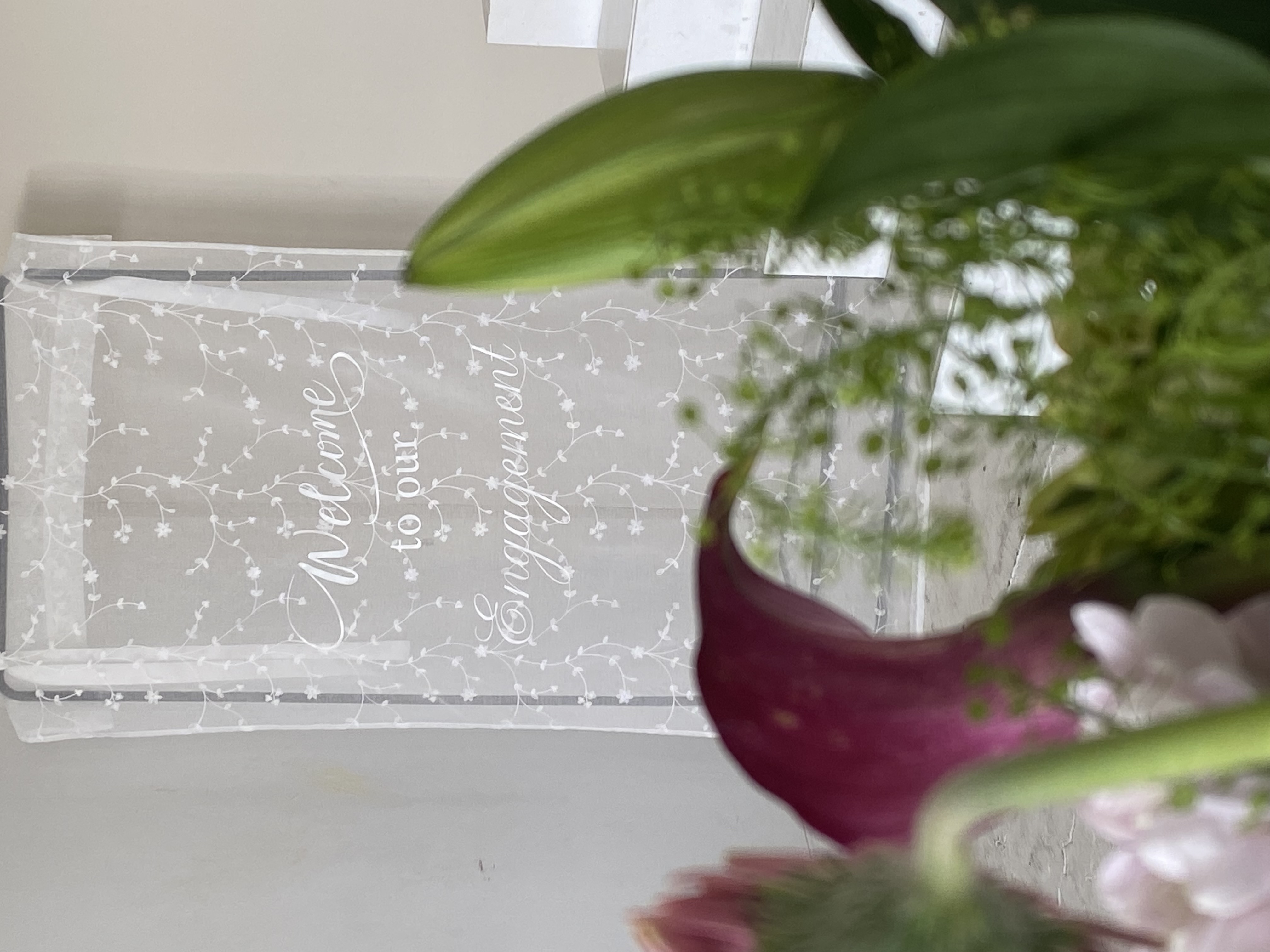 Acrylic welcome sign for engagement party with floral arrangement