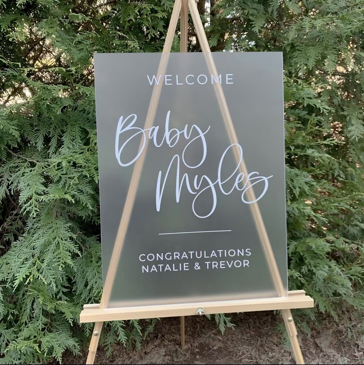 Frosted acrylic welcome sign with white lettering on a wooden easel