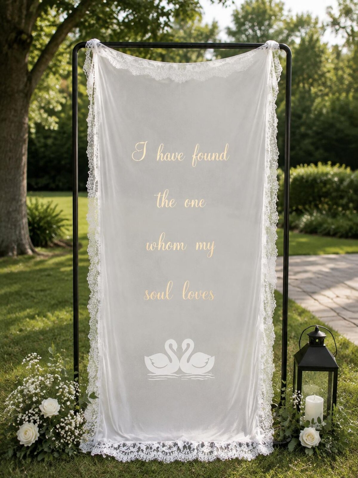 Sheer lace-trimmed welcome banner with gold script lettering on a garden stand